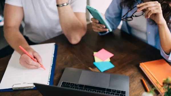 Cropped image of two people making notes while working collaboratively